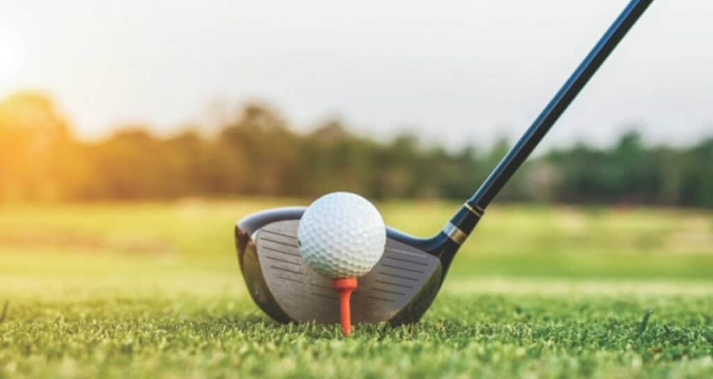 Balle de golf sur un tee devant un bâton de golf