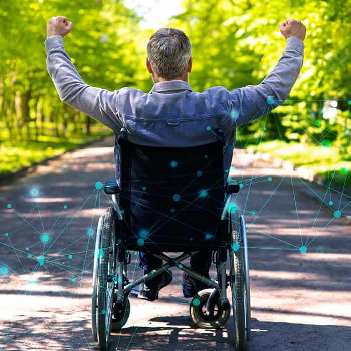 Homme en fauteuil roulant de dos et levant les bras en signe de victoire