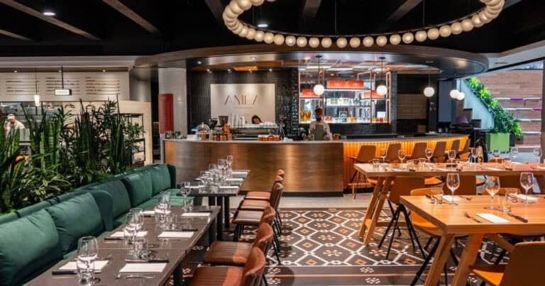 Intérieur élégant du café AMEA. Banquettes vertes, tables dressées, bar circulaire éclairé.