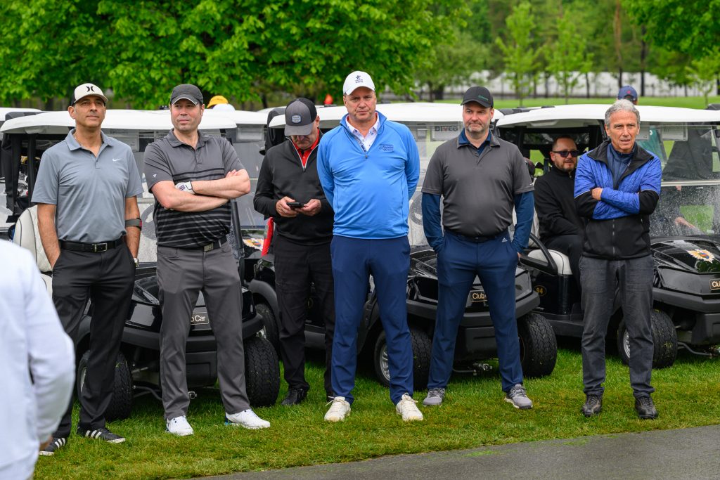 Groupe d'hommes en tenue de golf posant devant des voiturettes de golf