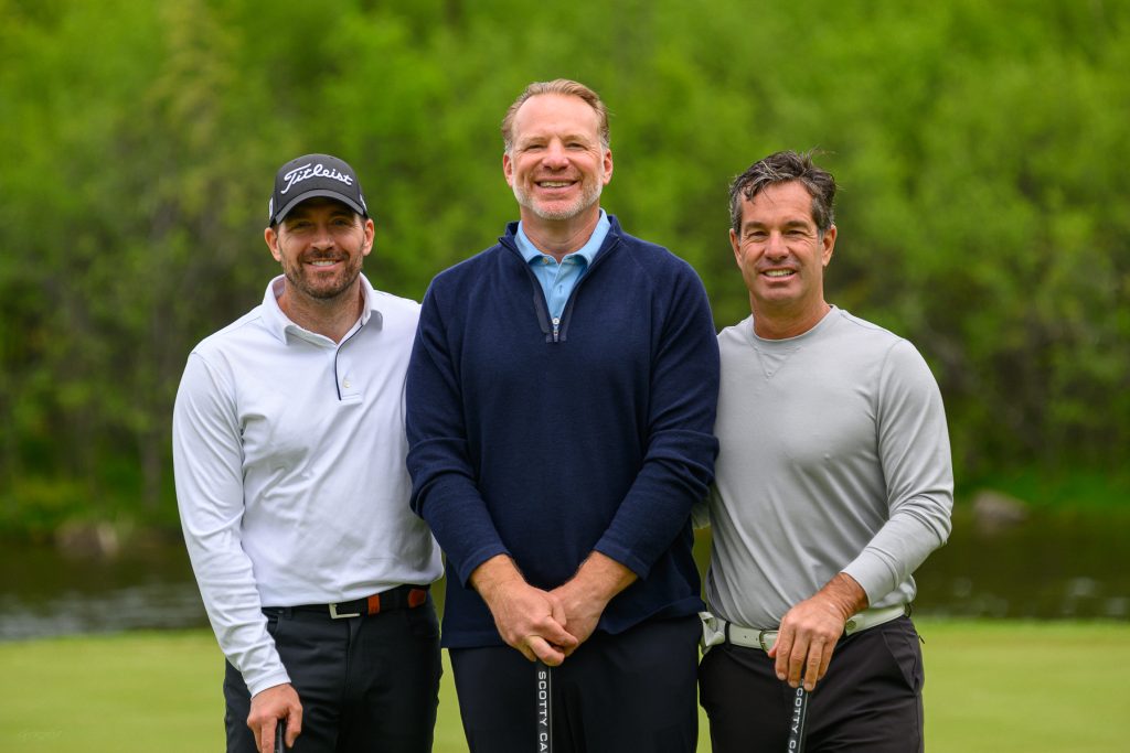 Trois golfeurs souriants sur un parcours de golf verdoyant